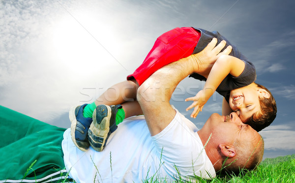 Stock photo: A parent and his kid laying and smiling on grass