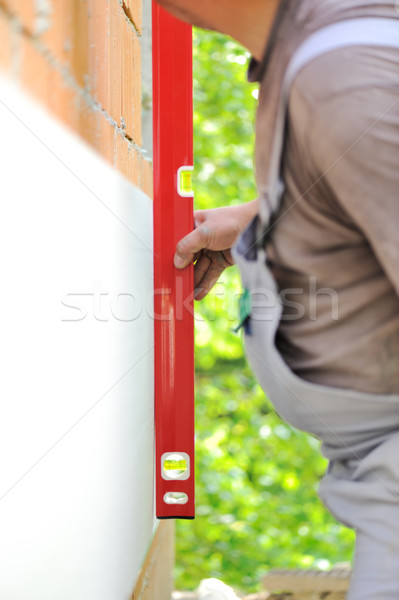 Construction worker checking vertical level with leveling tool Stock photo © zurijeta