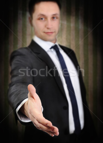 Successful young man extending hand to shake, on grunge vintage wall background Stock photo © zurijeta