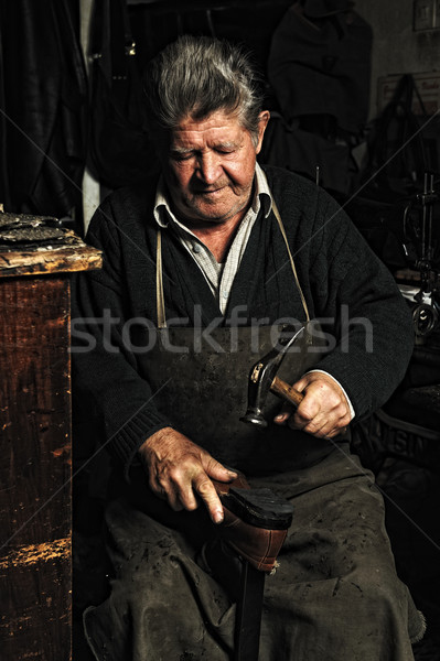 Old man, shoemaker, repairing old handmade shoe in his workshop Stock photo © zurijeta
