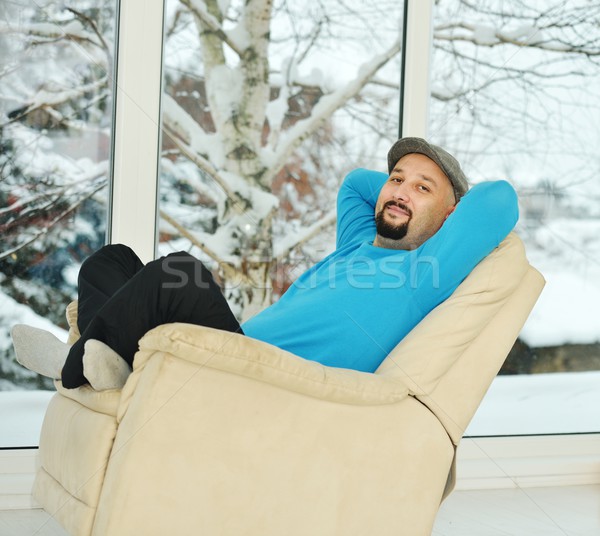 Young man relaxing on a white sofa at home by winter snow time Stock photo © zurijeta