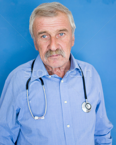 Portrait of a senior doctor on blue medical background Stock photo © zurijeta