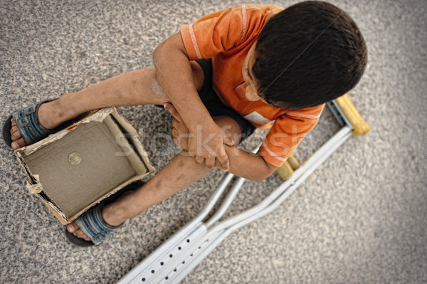 Hungry kid begging on the street with a crutches beside Stock photo © zurijeta