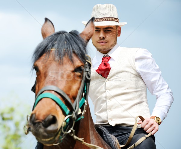 Young stylish man taking riding a horse on countryside Stock photo © zurijeta