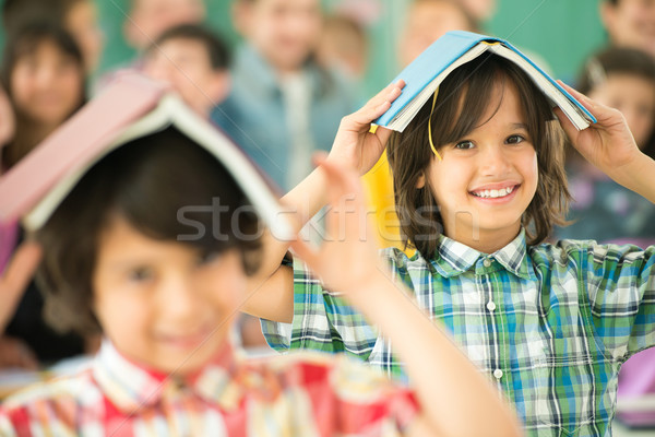 Group of children with books on heads smiling in classroom Stock photo © zurijeta